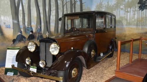 Vintage car in front of a painted wilderness background
